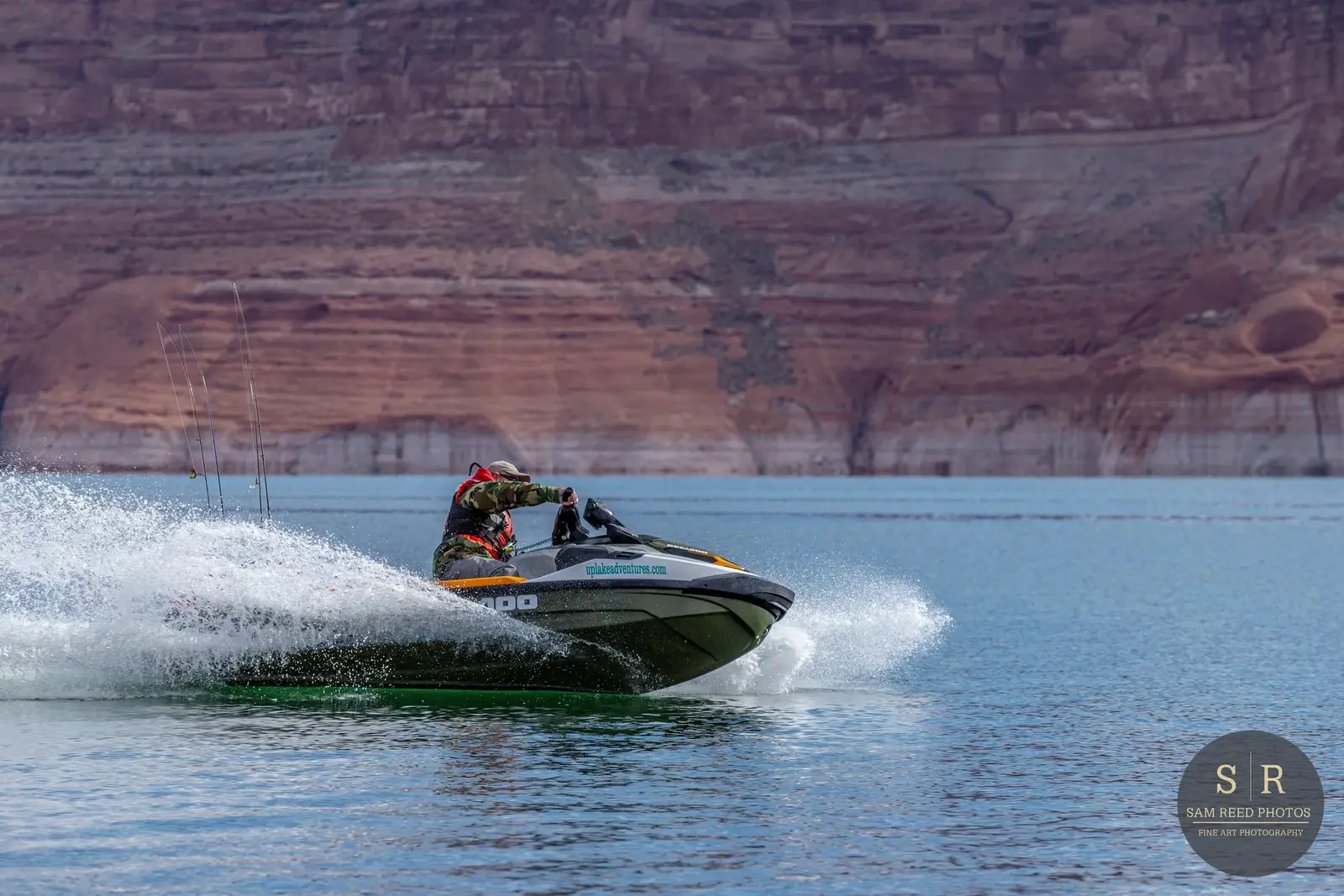 A person riding a jet ski on a large body of water with canyon walls in the background.
