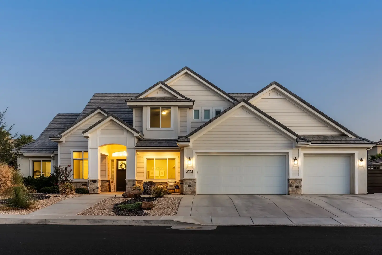 Two-story home with an illuminated entry and attached garage at dusk.