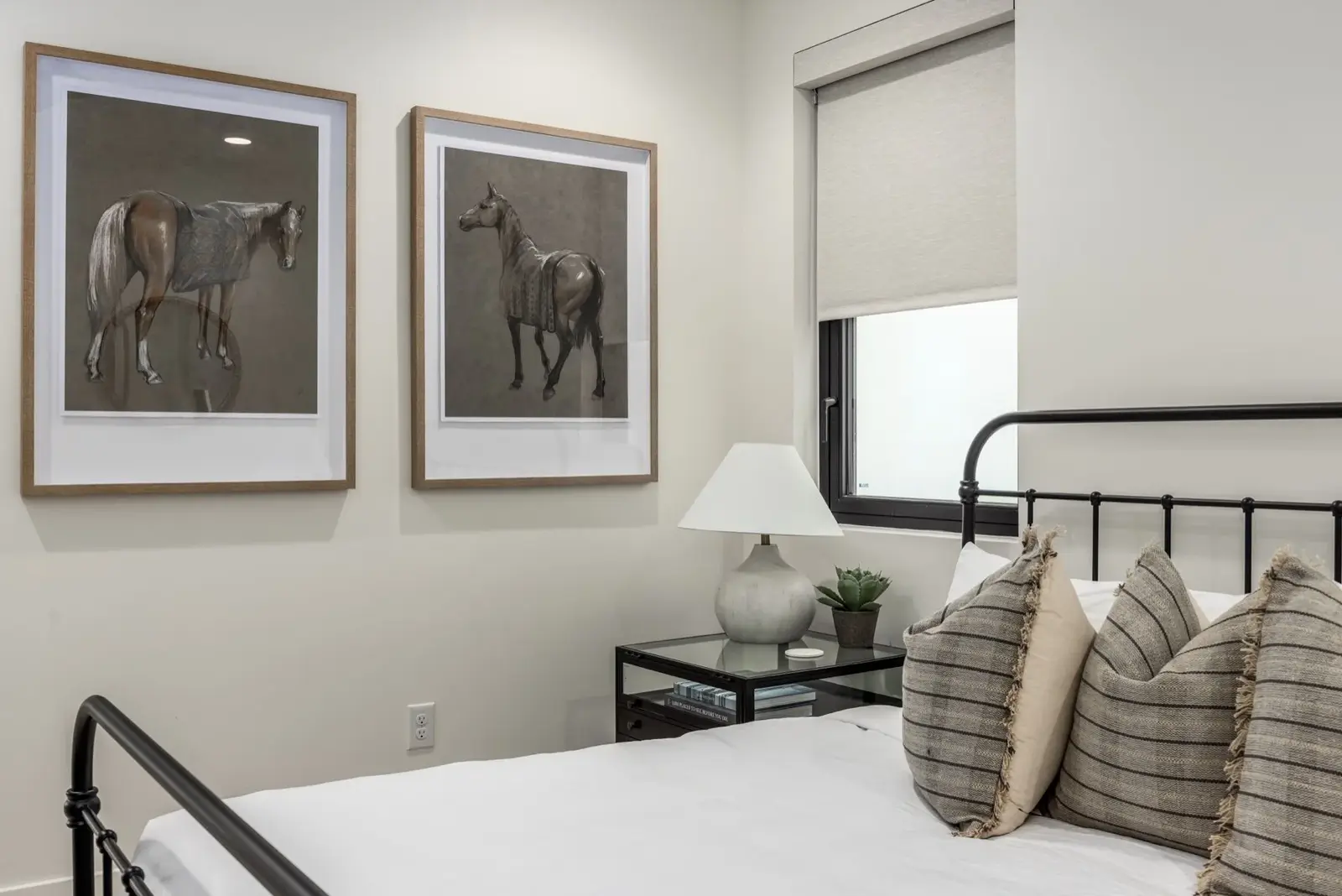 Lula Bay — Guest bedroom with an iron bed and framed horse artwork