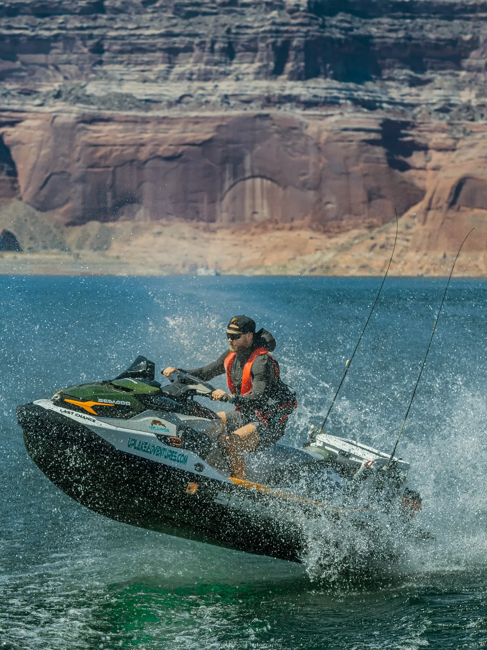 A person riding a jet ski on a lake with a canyon in the background, wearing sunglasses and a life jacket.
