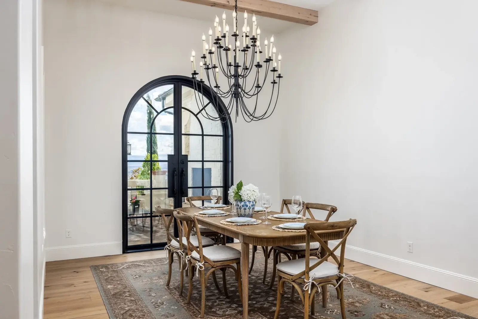 Dining table beneath a chandelier beside an arched glass doorway at the Sunset property