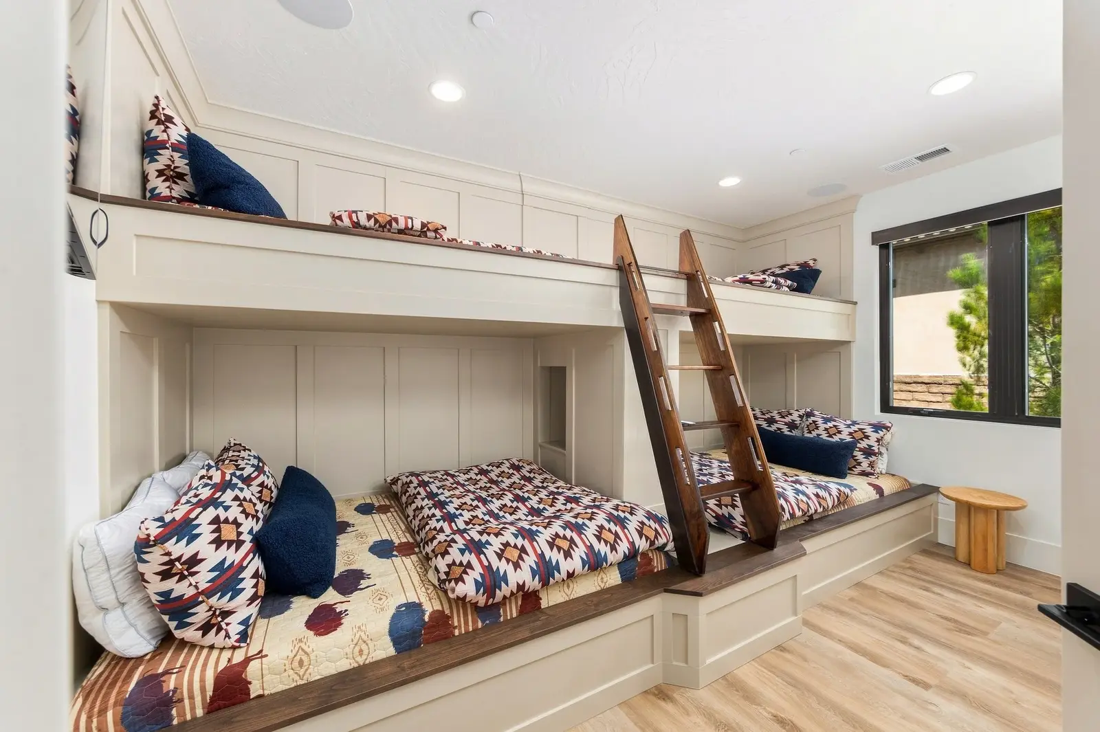 Built-in bunk beds with patterned bedding and a wooden ladder