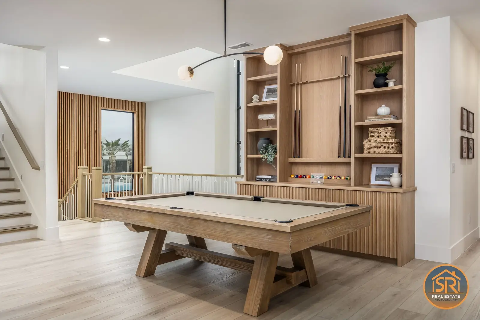 Pool table in a bright recreation room with built-in wood shelving — from Sam Reed’s photography portfolio