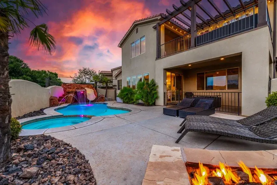 Illuminated home and pool beneath an orange twilight sky photographed by Sam Reed