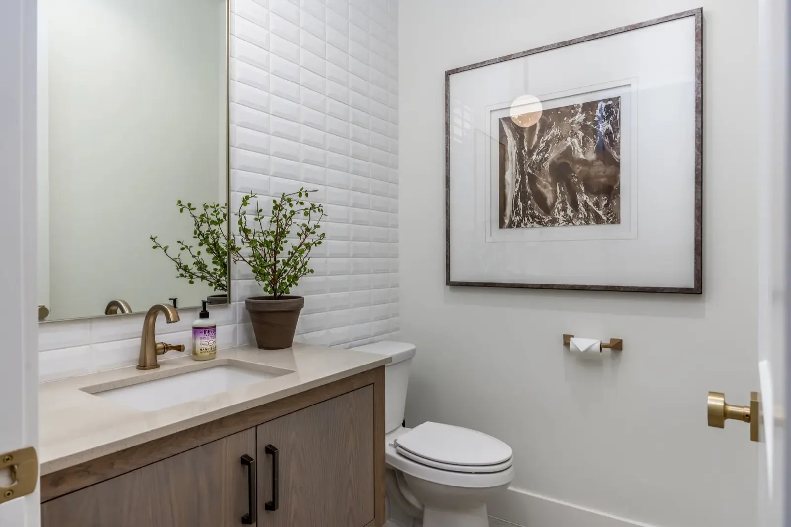 Lula Bay — Powder room with framed artwork and brass fixtures