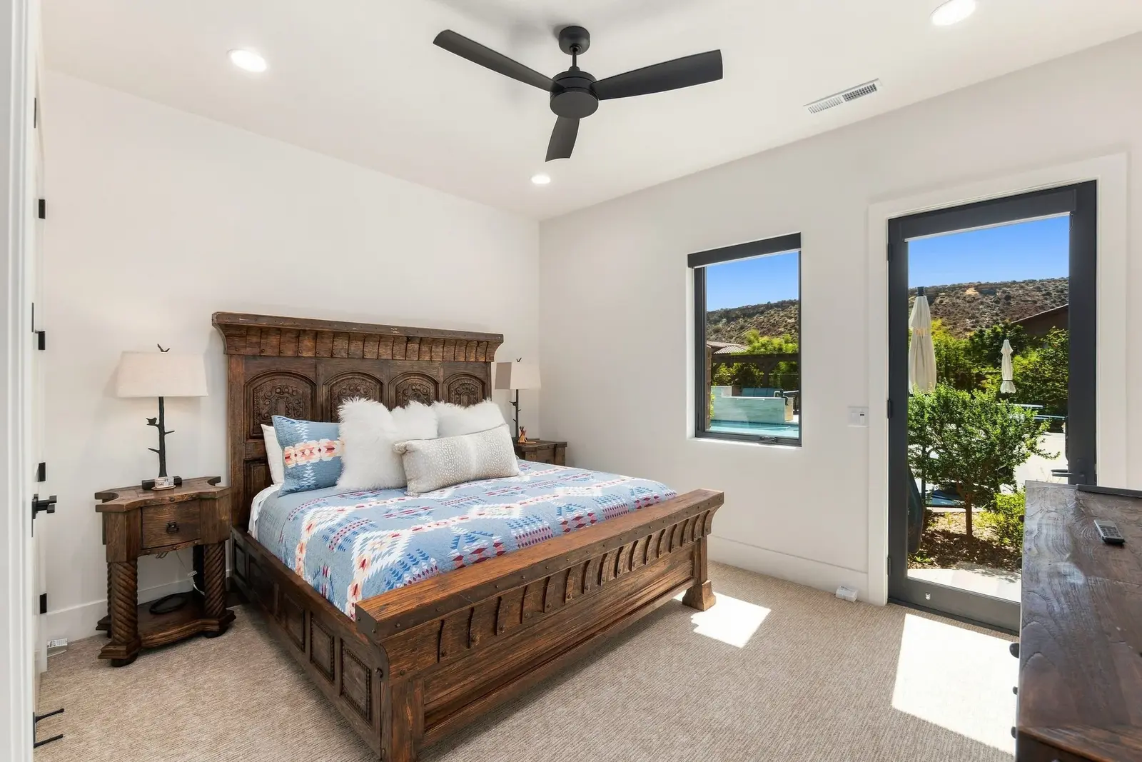 Furnished bedroom with a wood bed and windows overlooking landscaping