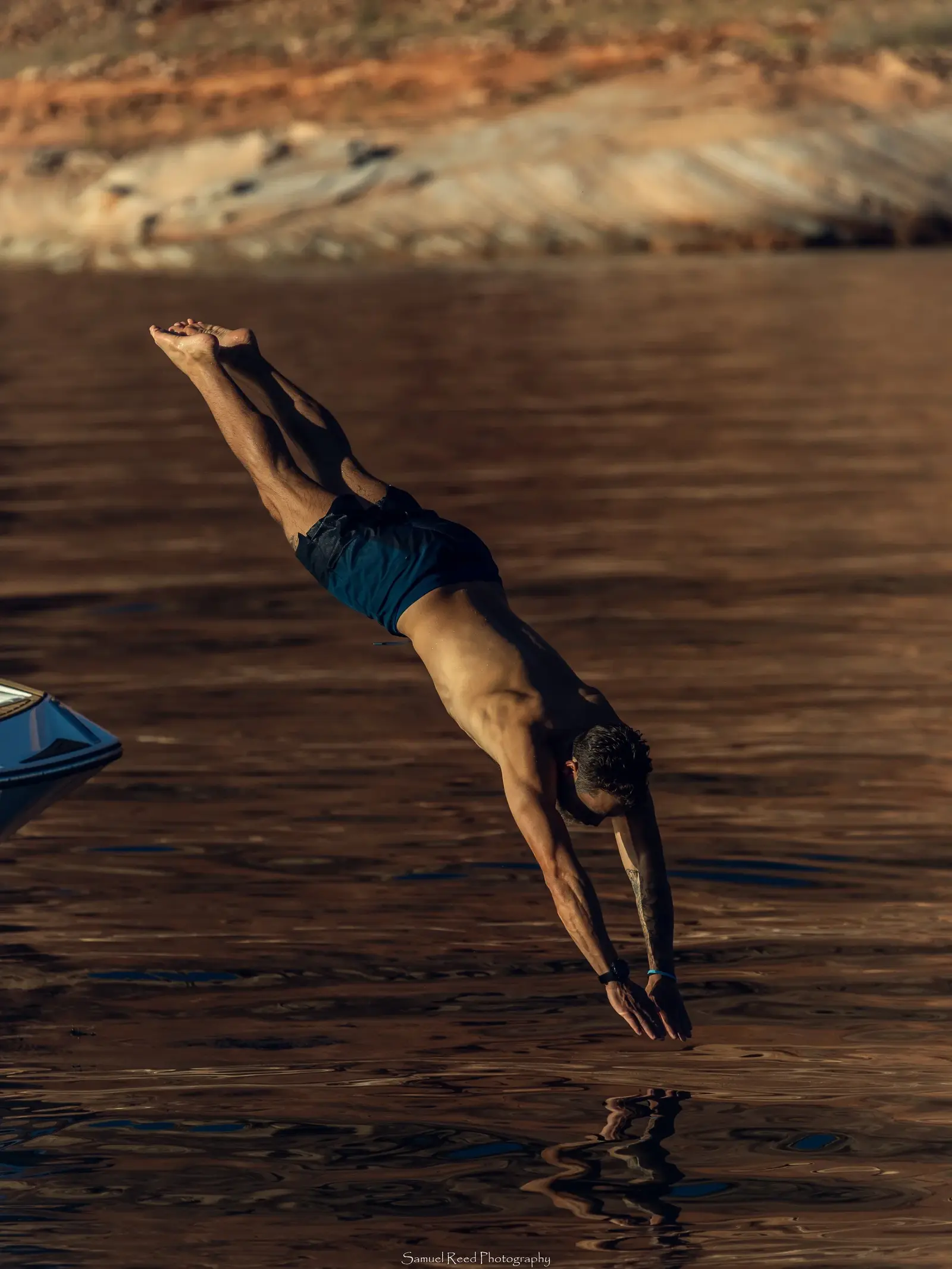 A man diving into a body of water during sunset.