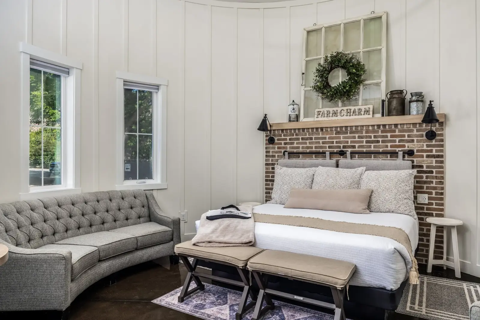 Guest suite with a brick accent wall, bed and upholstered sofa at The Silo Suites