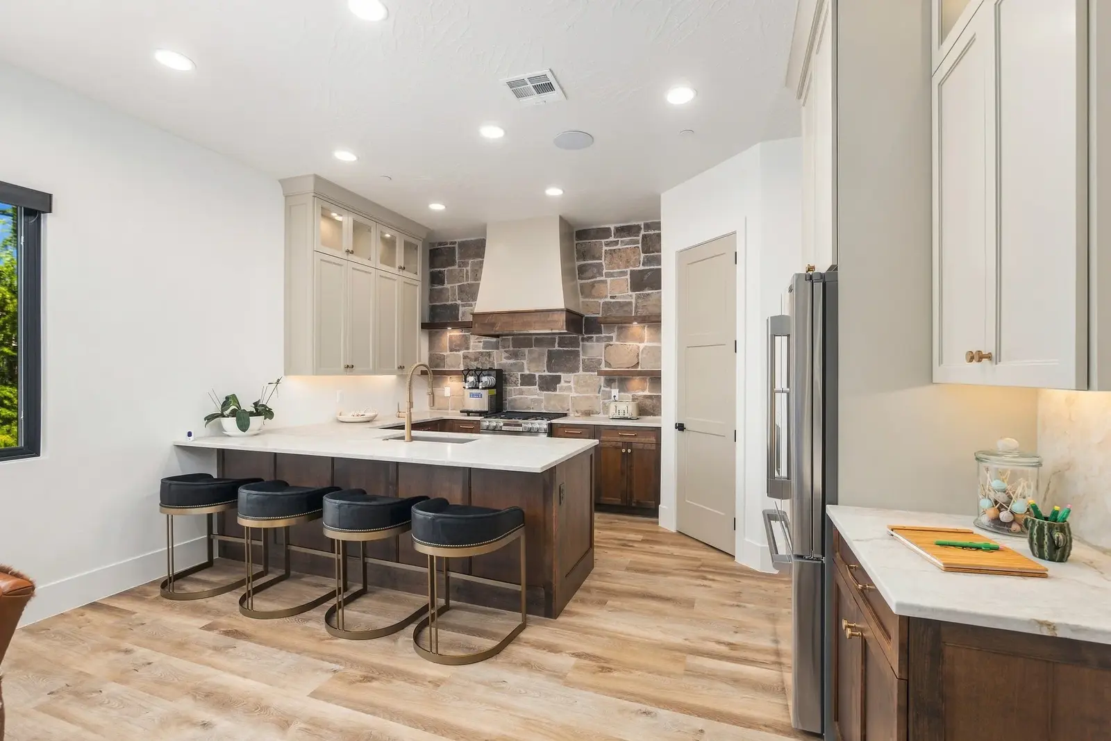 Kitchen with a stone backsplash and four stools at the island
