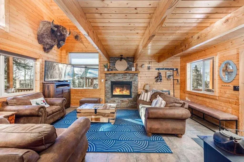 Brian Head cabin living room with timber walls, leather seating and a stone fireplace — photographed by Sam Reed