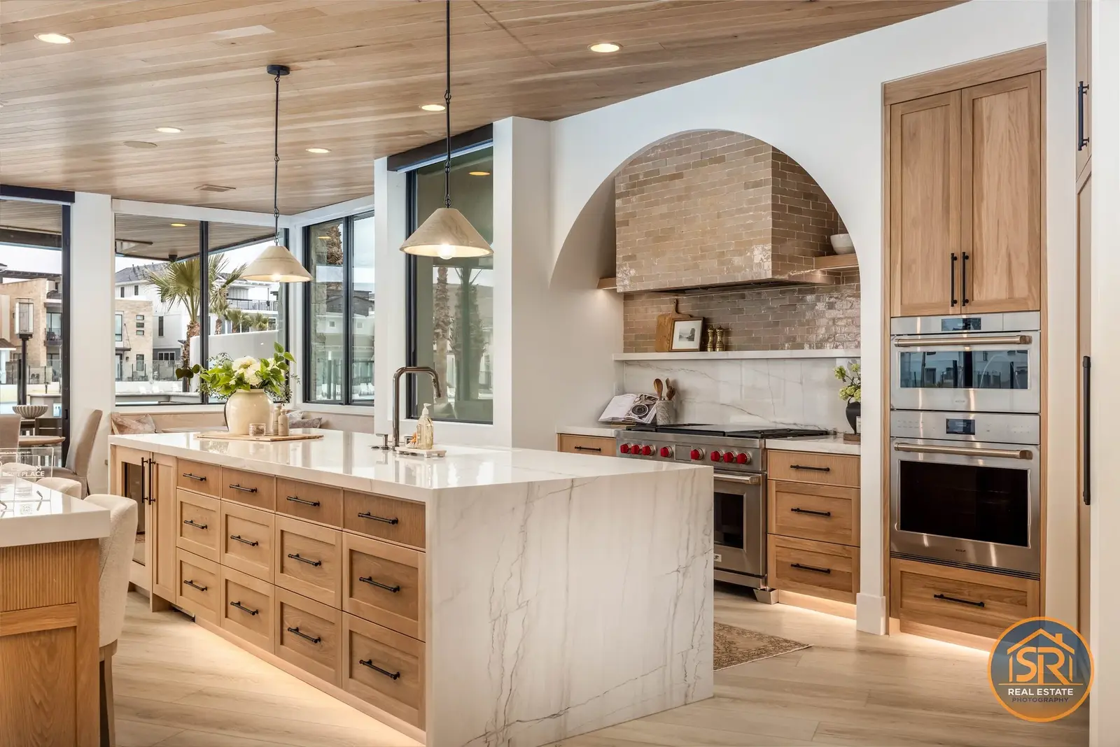 Wood kitchen cabinetry and a stone island beneath an arched range alcove — from Sam Reed’s photography portfolio