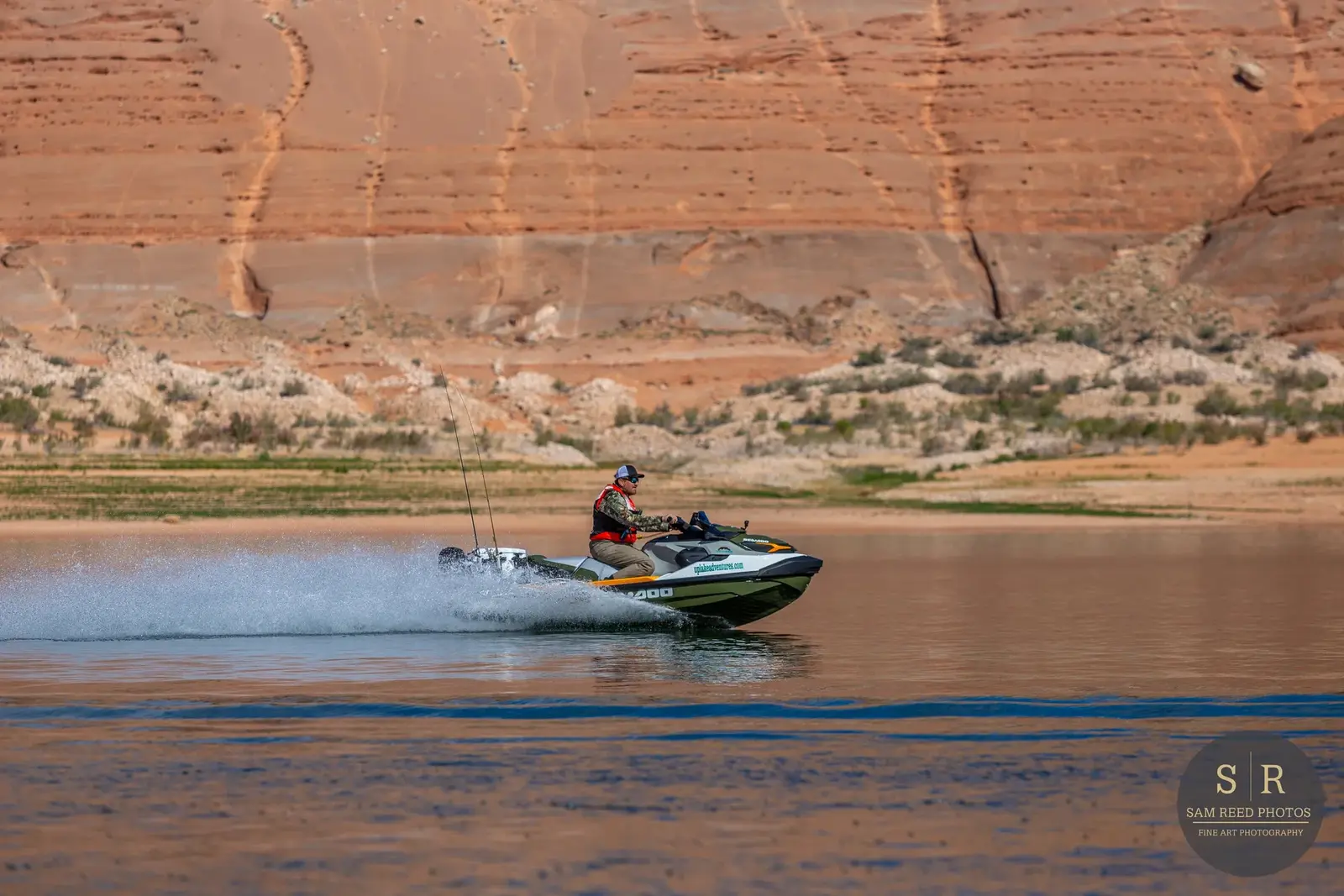 A person riding a jet ski on a body of water with a mountainous desert landscape in the background.