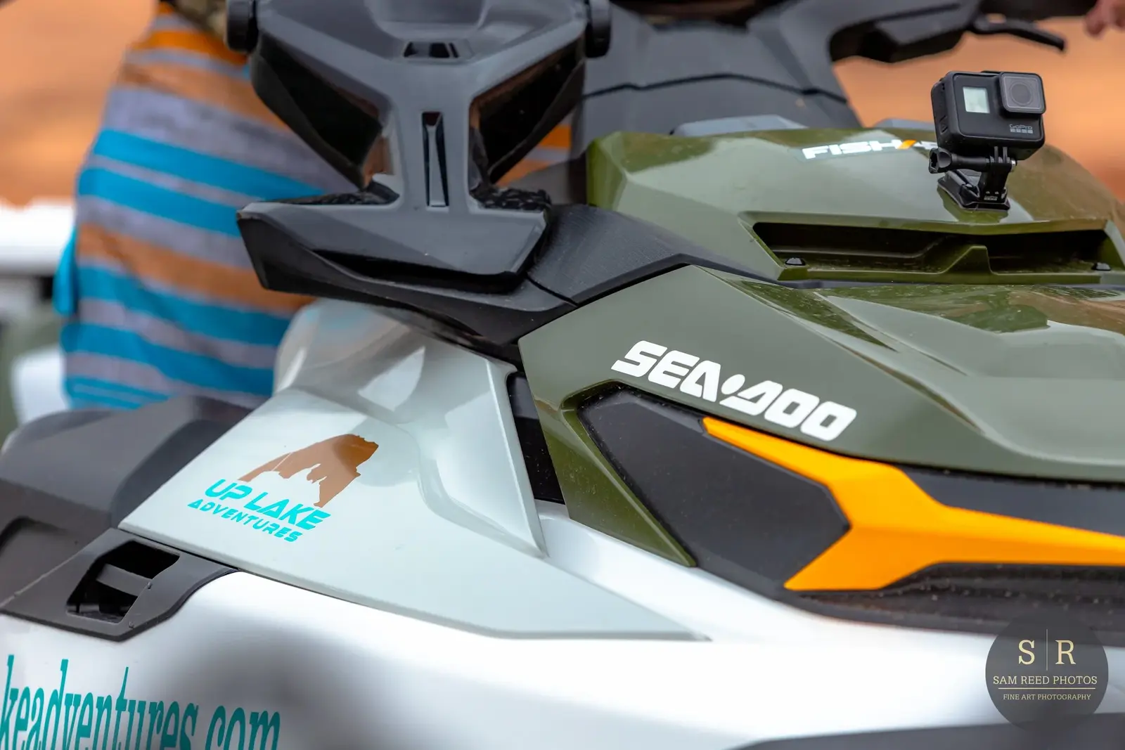 Close-up of a Sea-Doo personal watercraft with a GoPro camera mounted on the front, featuring rider gear and stickers that say 'UP LAKE ADVENTURES' and 'sea-doo'.