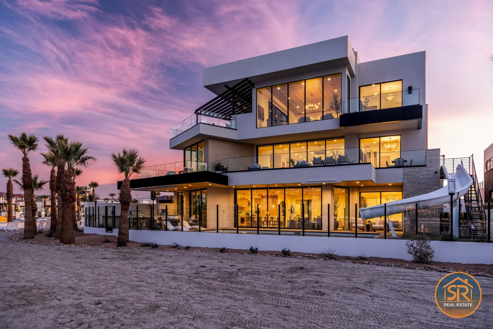 Modern multi-story home with illuminated windows beneath a colorful twilight sky.
