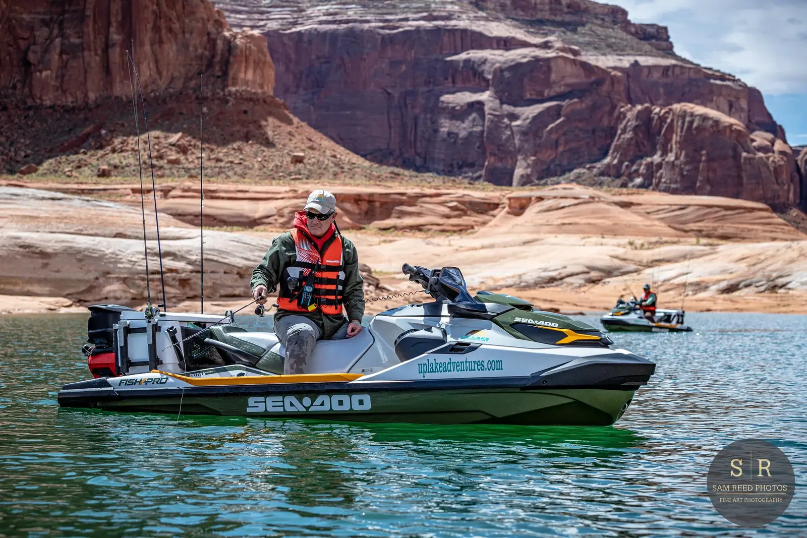 Two people on Sea-Doo jet skis in a lake surrounded by red rock formations.
