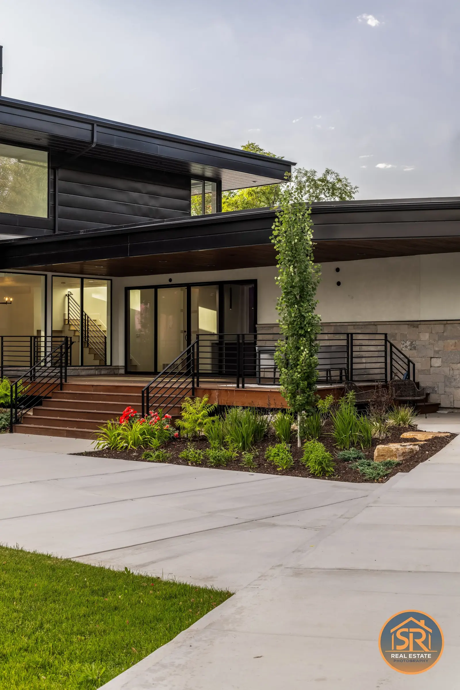 Covered terrace with dark siding, stonework and landscaped garden — from Sam Reed’s photography portfolio