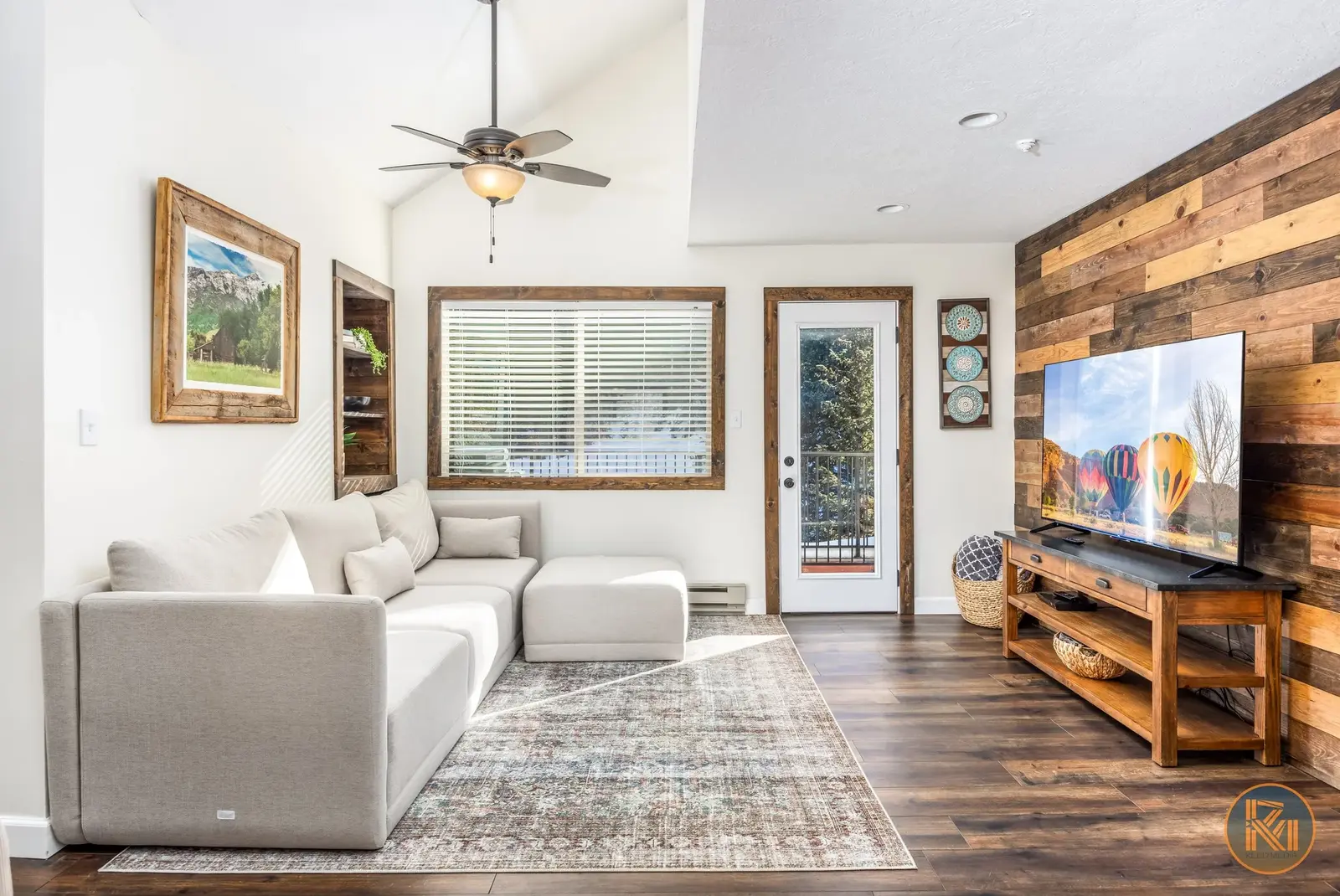 Living room with a gray sectional and a television on a wood accent wall.