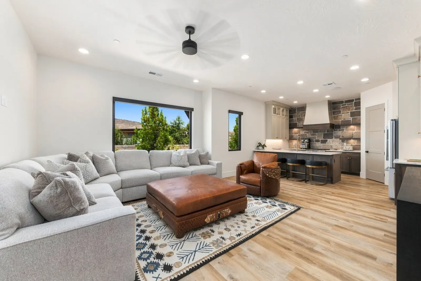 Furnished open-plan living room with a gray sectional sofa and adjoining kitchen