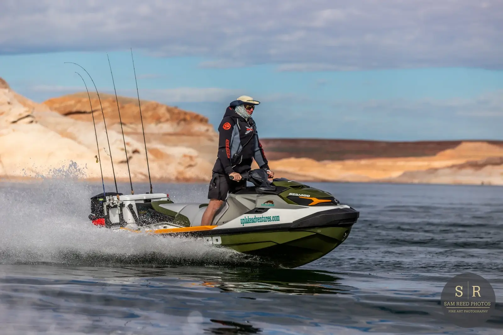 A person riding a Sea-Doo personal watercraft on a lake with rocky cliffs in the background.