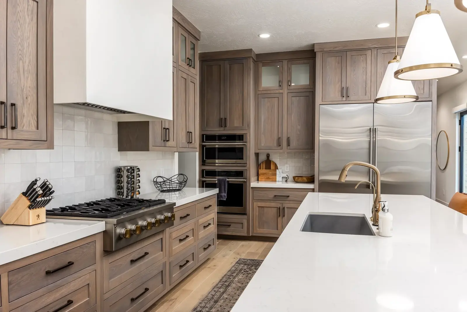 Lula Bay kitchen with wood cabinetry, a white island and brass fixtures — photographed by Sam Reed