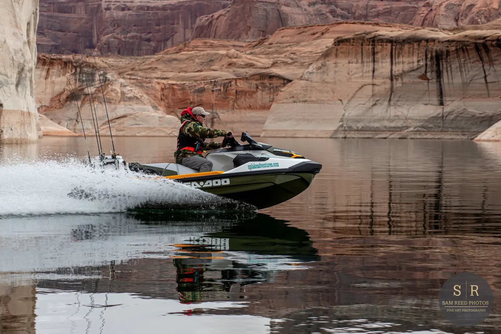 A man riding a jet ski on a calm body of water with canyon walls in the background.