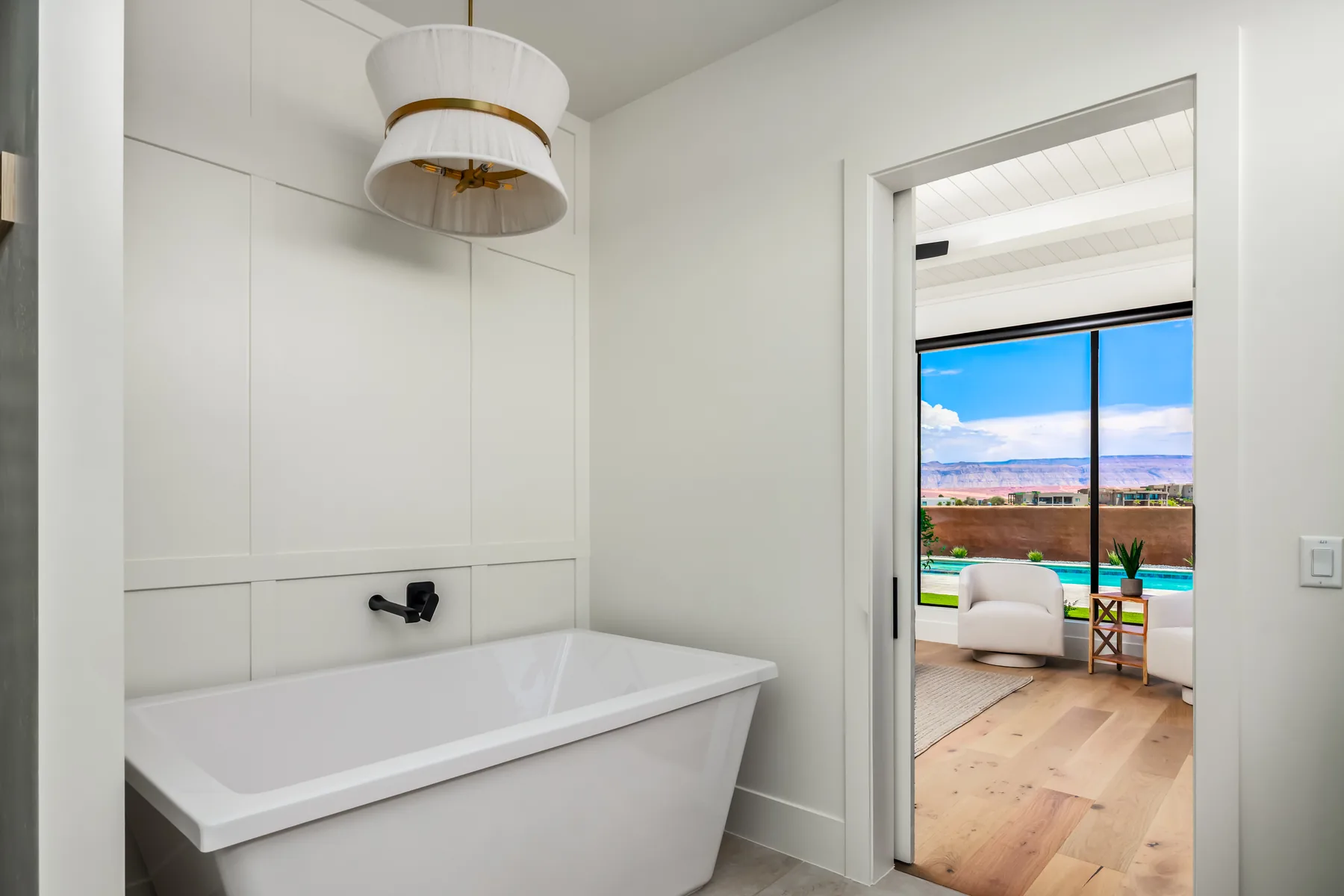 Freestanding bathtub and paneled wall with a doorway framing the pool-facing bedroom